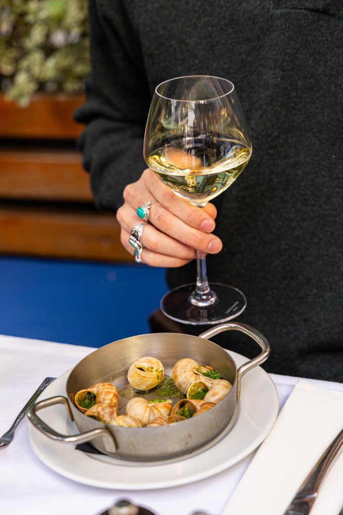 Escargots et une main tenant un verre de Vin